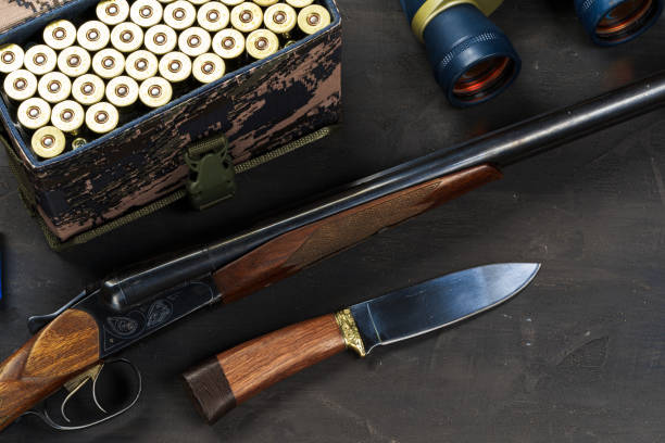 Hunting rifle and cartridges on dark wooden background, close up
