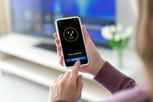 Female hands holding phone with face ID scanning on the screen in room home